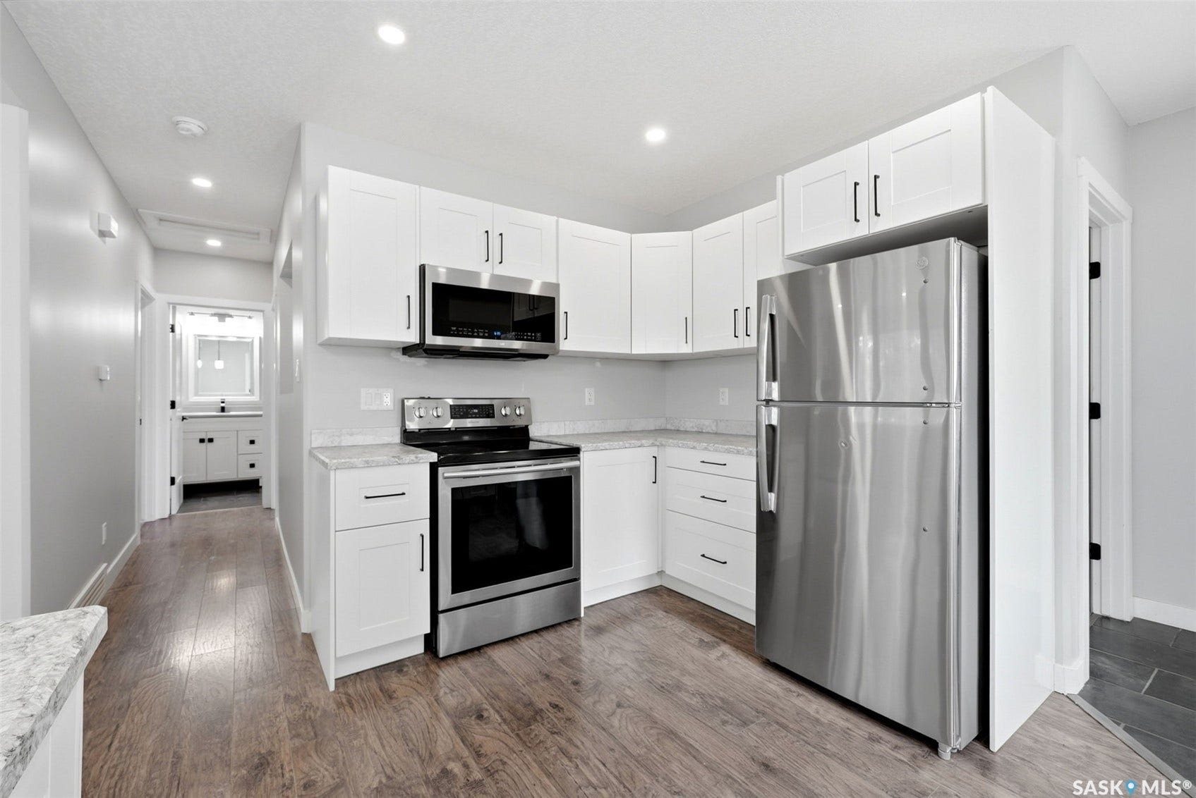 1601 Lacon Street, Regina SK S4N 1Z5 Kitchen featuring white cabinetry, stainless steel appliances, light-toned countertops, wood-finish flooring, and recessed lighting