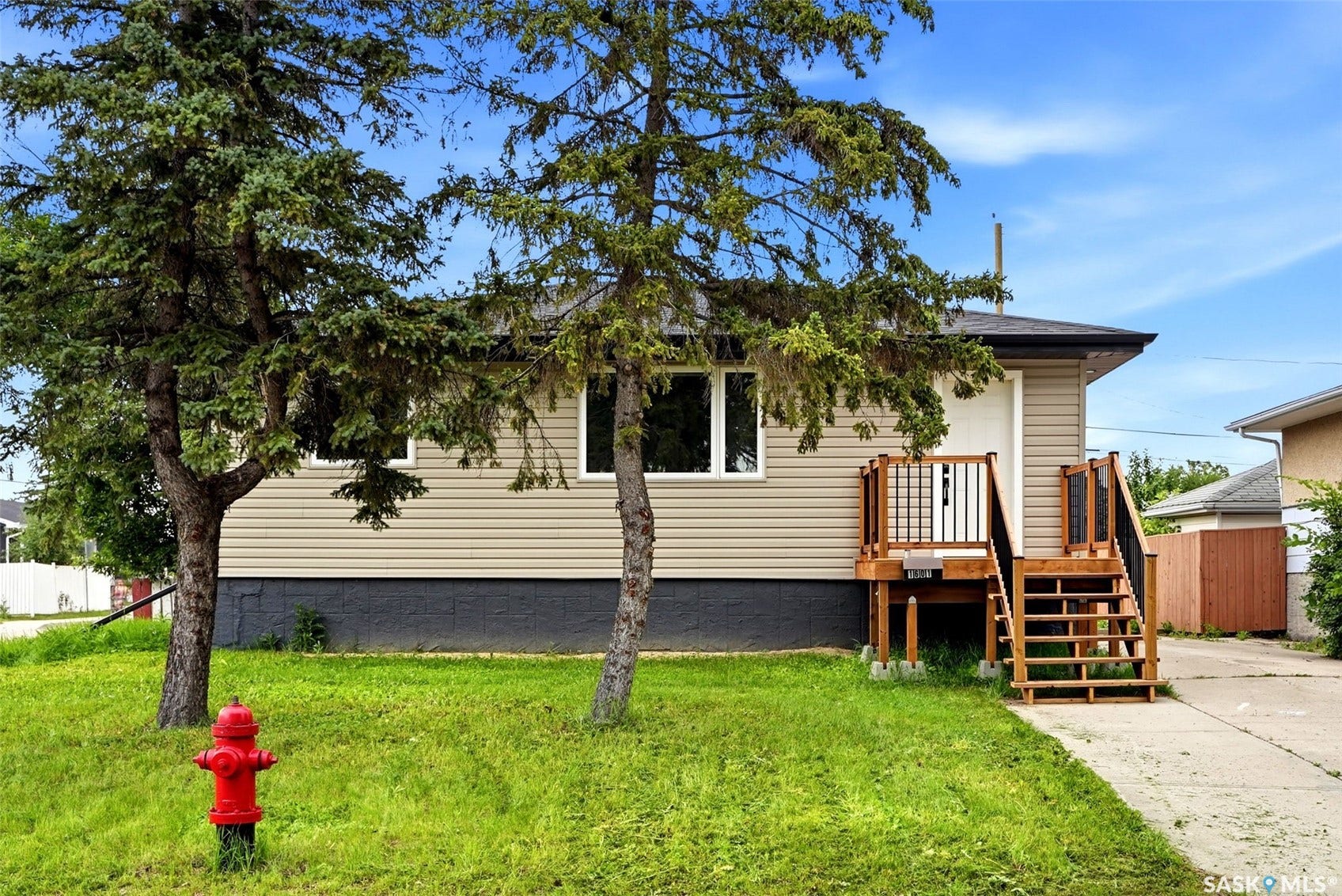 1601 Lacon Street, Regina SK S4N 1Z5 Exterior featuring tan horizontal siding, dark foundation, and a newly constructed wooden deck with stairs and railings