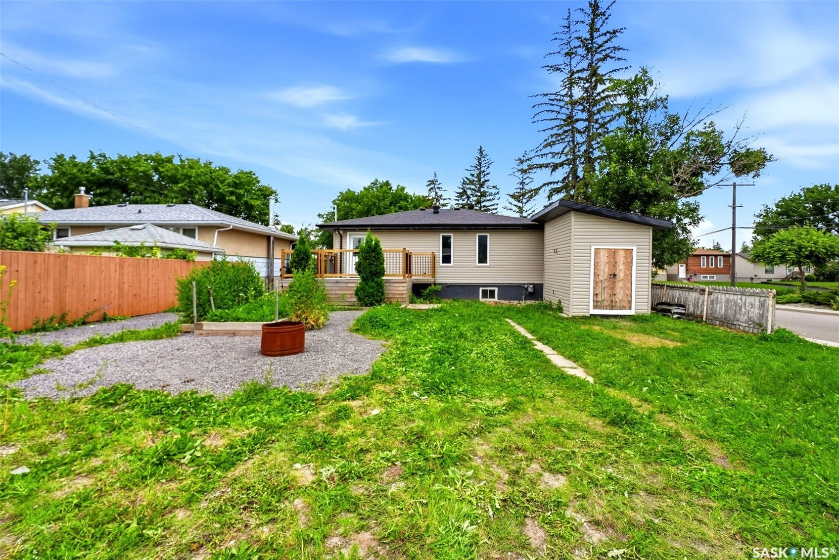 1601 Lacon Street, Regina SK S4N 1Z5 Rear exterior featuring a wood deck, gravel path, wood privacy fence, and a detached storage shed