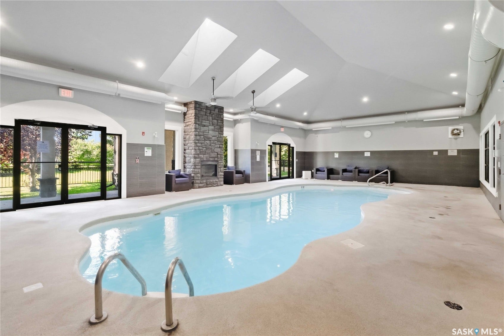 Indoor swimming pool with skylights, recessed lighting, and a stone-clad fireplace