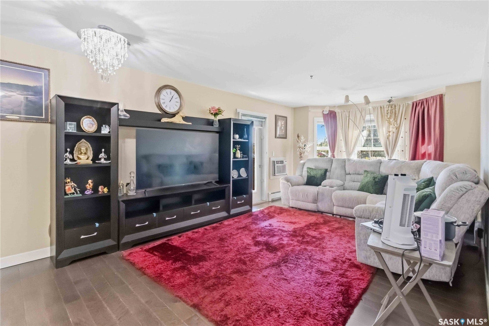 Wood-finish flooring, built-in entertainment center, and multiple windows with natural light