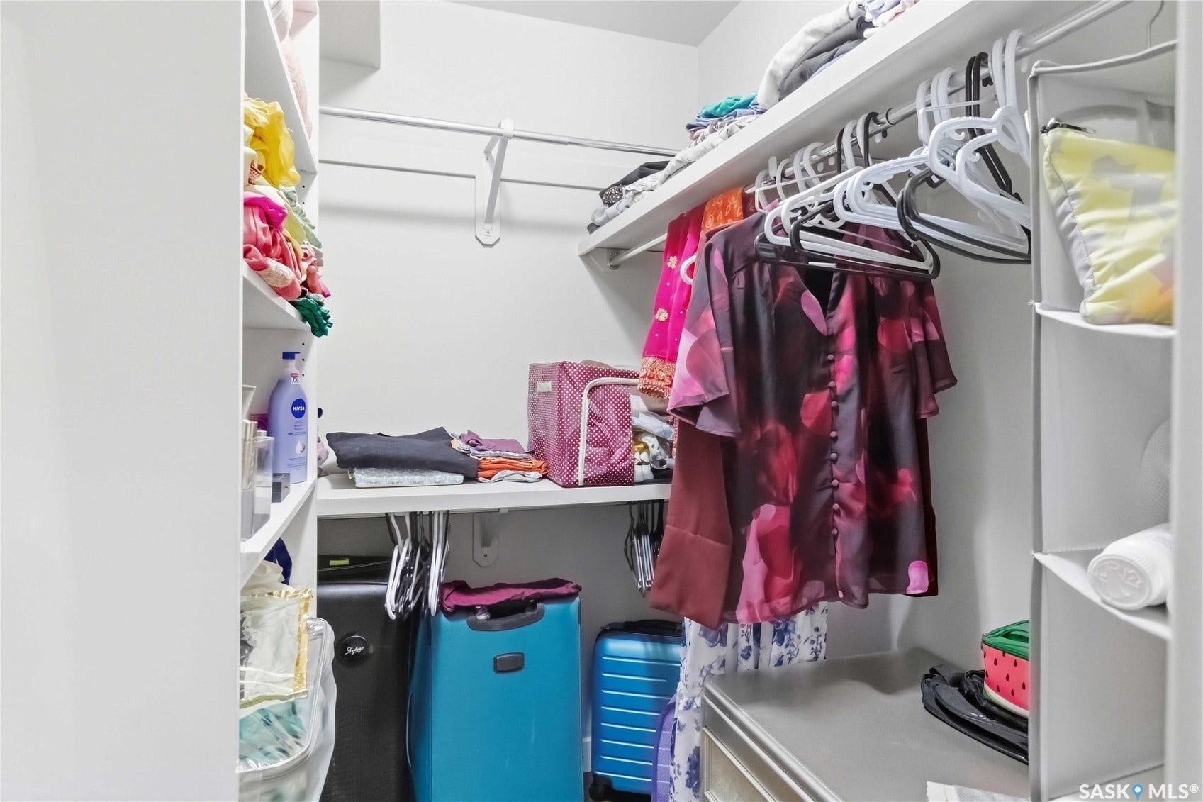 Built-in closet with white shelving, a hanging rod, and integrated storage compartments