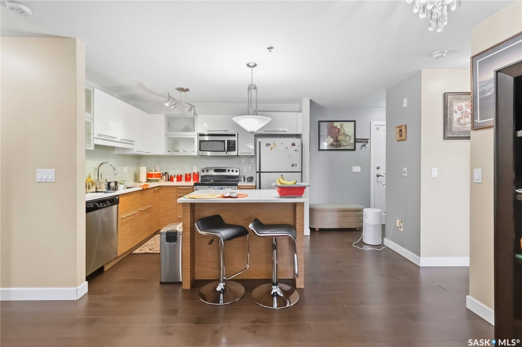 Contemporary kitchen featuring wood-finish flooring, two-tone cabinetry, stainless steel appliances, and a central island with a breakfast bar