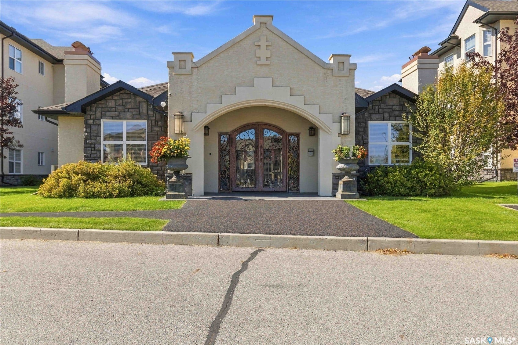 Stucco and stone exterior featuring an arched entryway with ornate double doors