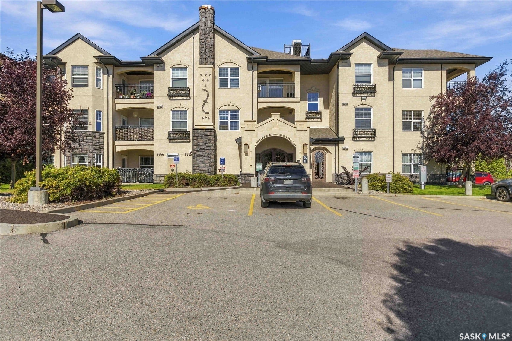 Multi-level building exterior featuring stone accents, stucco finish, multiple balconies, and an arched entry