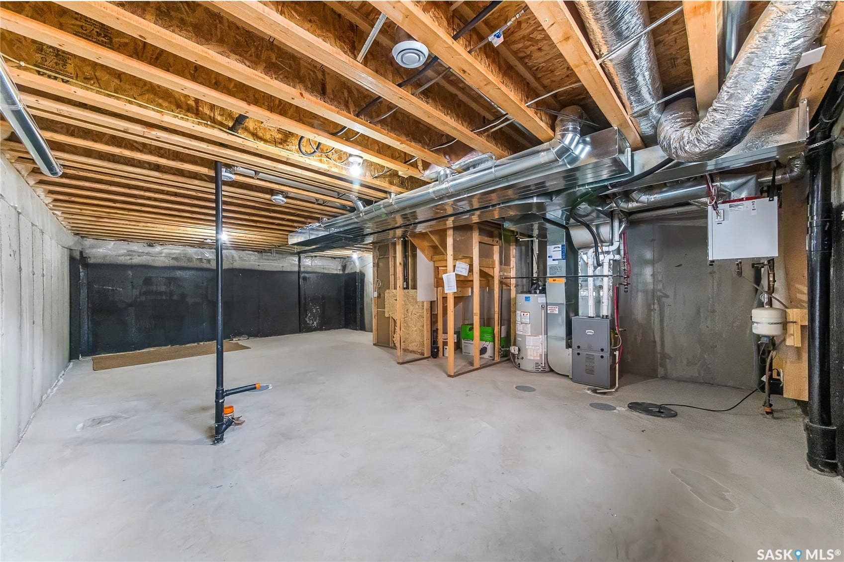 Unfinished basement with exposed ceiling joists, concrete flooring, and visible ductwork