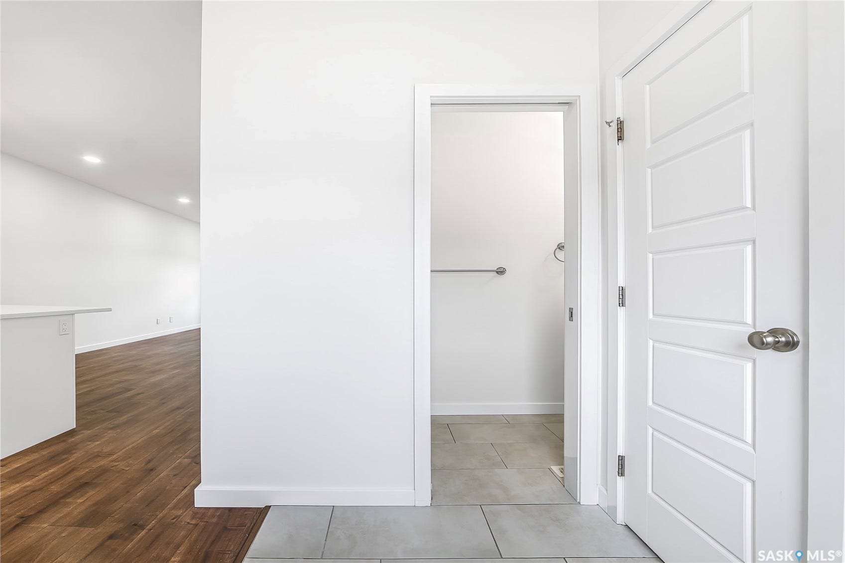 White five-panel door with brushed nickel hardware, light gray tiled flooring, and a towel bar