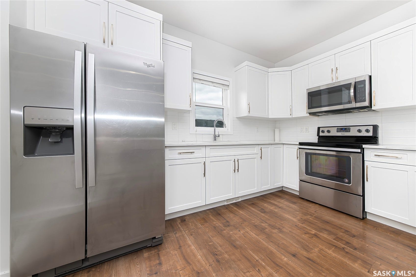 Full kitchen featuring wood-finish flooring, white cabinetry, stainless steel appliances, and white countertops