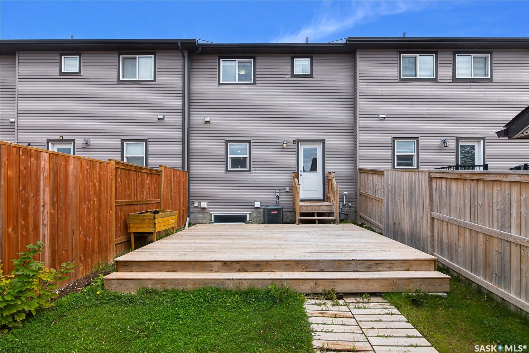 Rear exterior with a spacious wood deck, wood privacy fencing, and grey horizontal siding