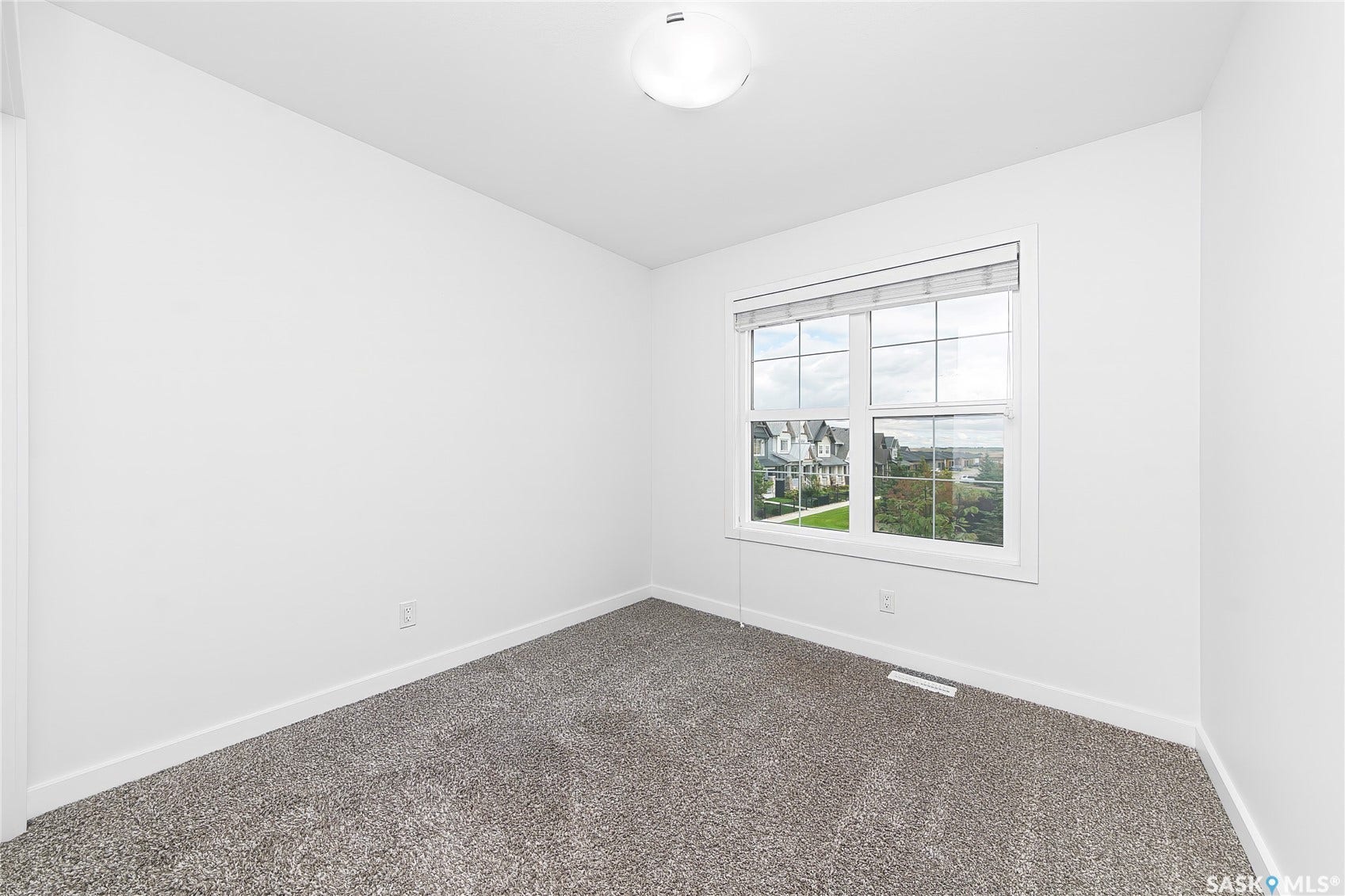 White interior walls, neutral tone carpeting, white window trim, and a semi-flush mount ceiling light fixture
