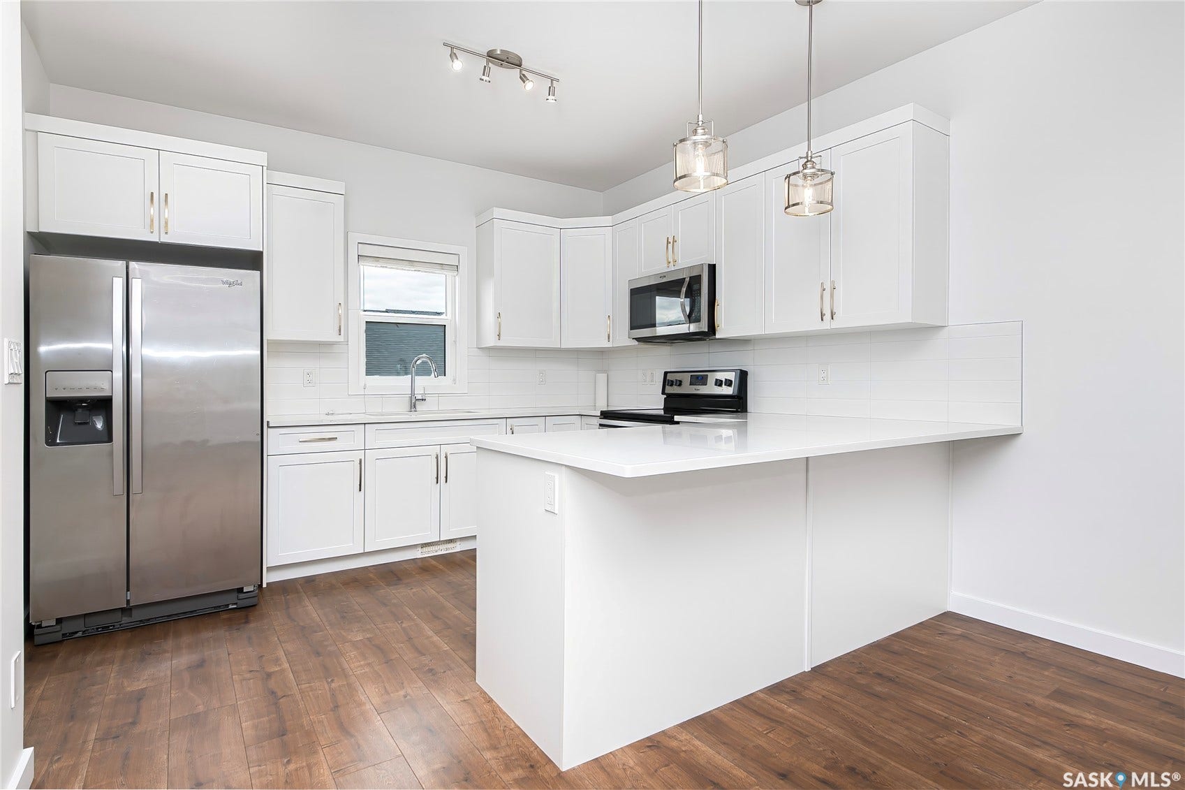 Kitchen featuring white cabinetry, stainless steel appliances, white subway tile backsplash, white countertops, and wood-finish flooring