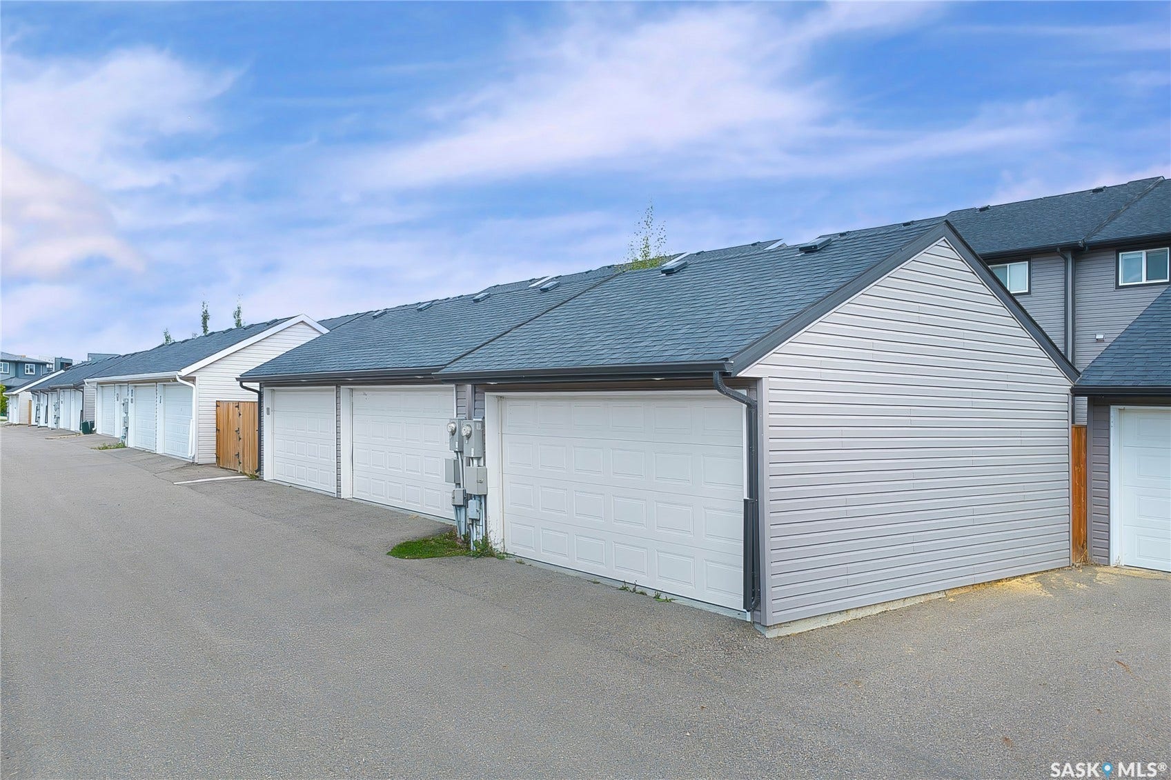 Multiple detached garages with white panel doors and gray siding