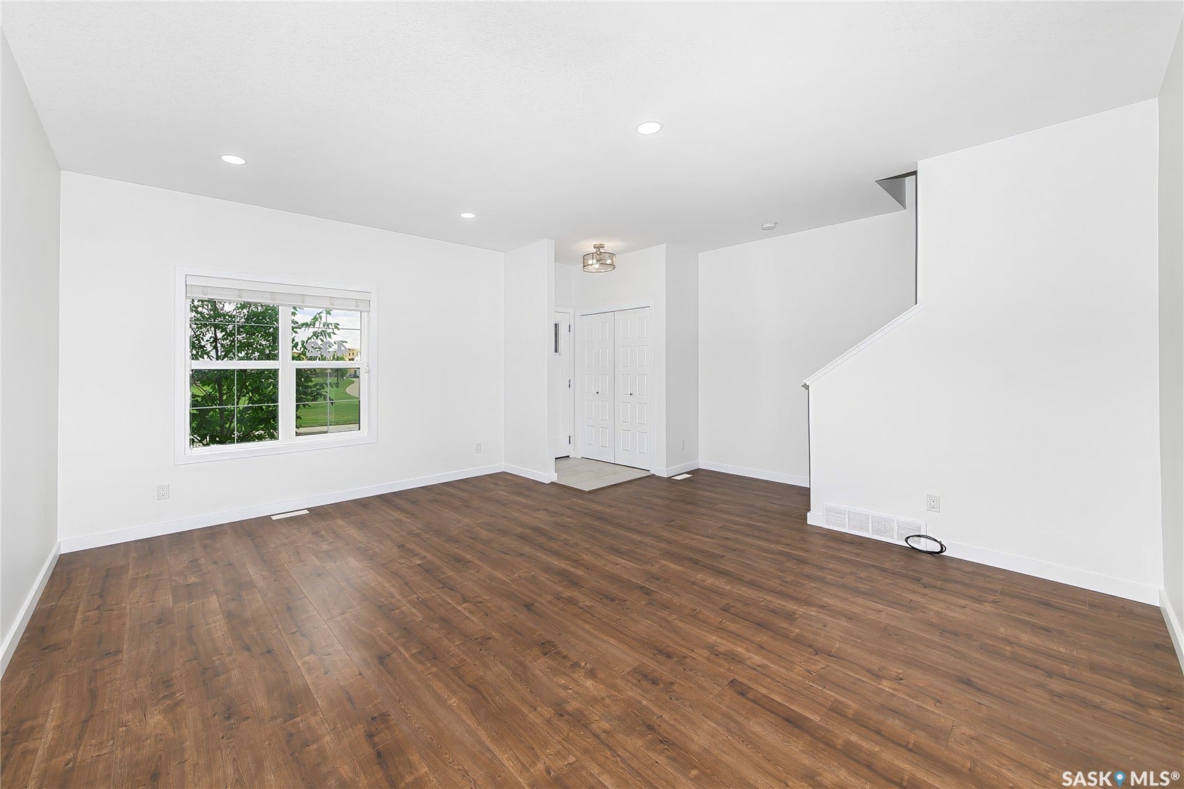 Wood-finish flooring, recessed lighting, white walls, and a window with blinds