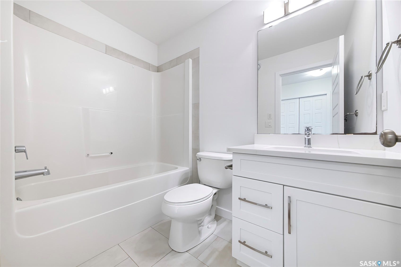 White vanity with a single basin sink, chrome faucet, and quartz countertop