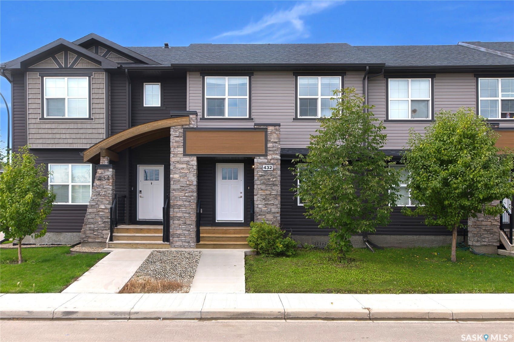 Contemporary townhome exterior featuring multi-toned siding, stone accents, and a dark shingle roof