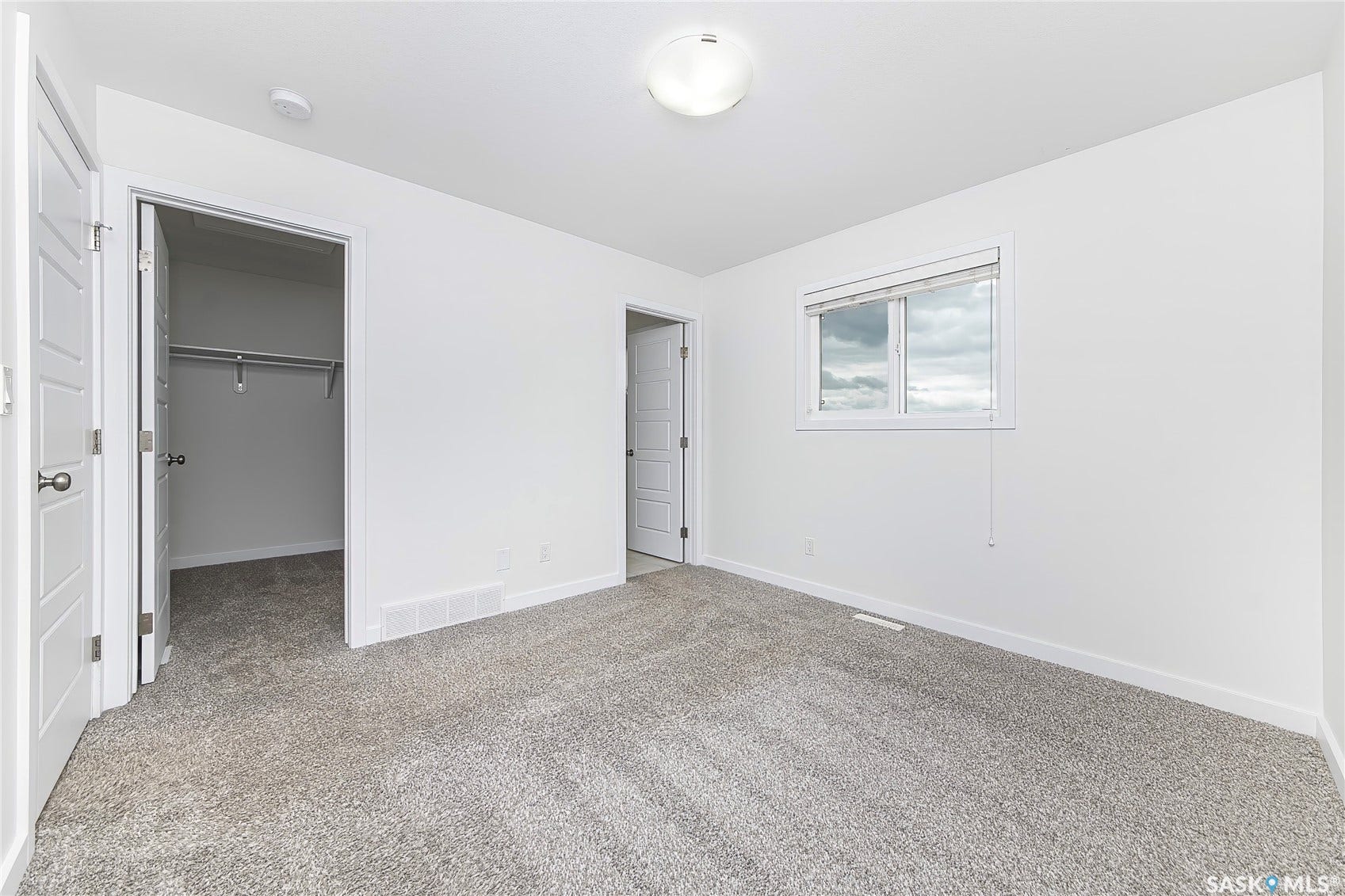 Neutral-toned carpeted flooring, white painted walls, and a window with blinds