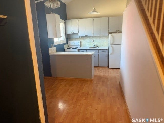 Kitchen featuring wood-finish flooring, white cabinetry, and a tile backsplash