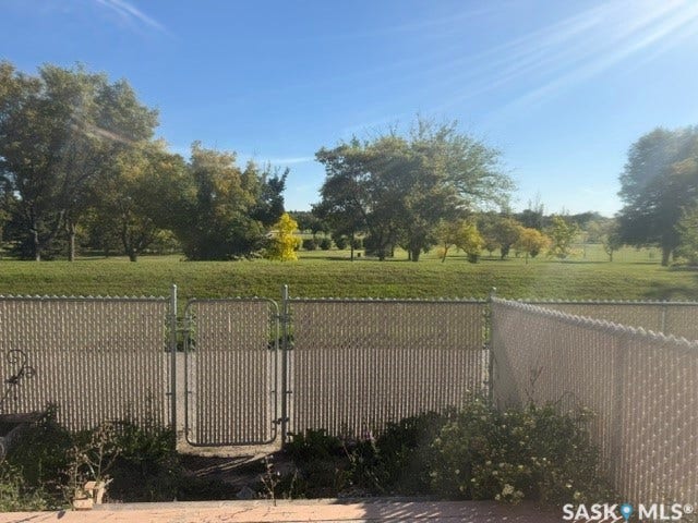 Expansive green space backing the property, featuring mature trees and a chain-link fence with a gate