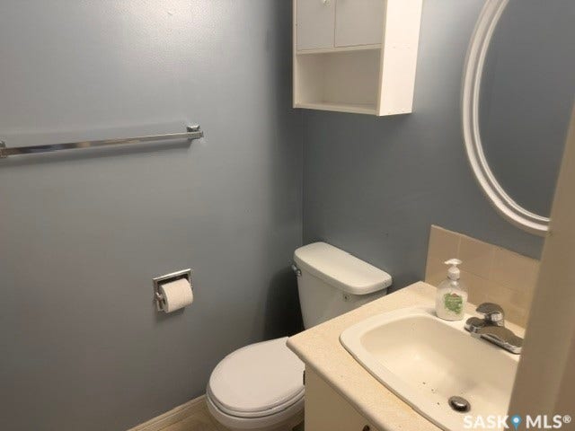 White vanity with an integrated sink, a chrome faucet, and an oval mirror