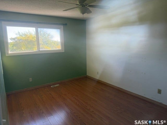 Wood-finish flooring, white window trim, and a ceiling fan with integrated lighting
