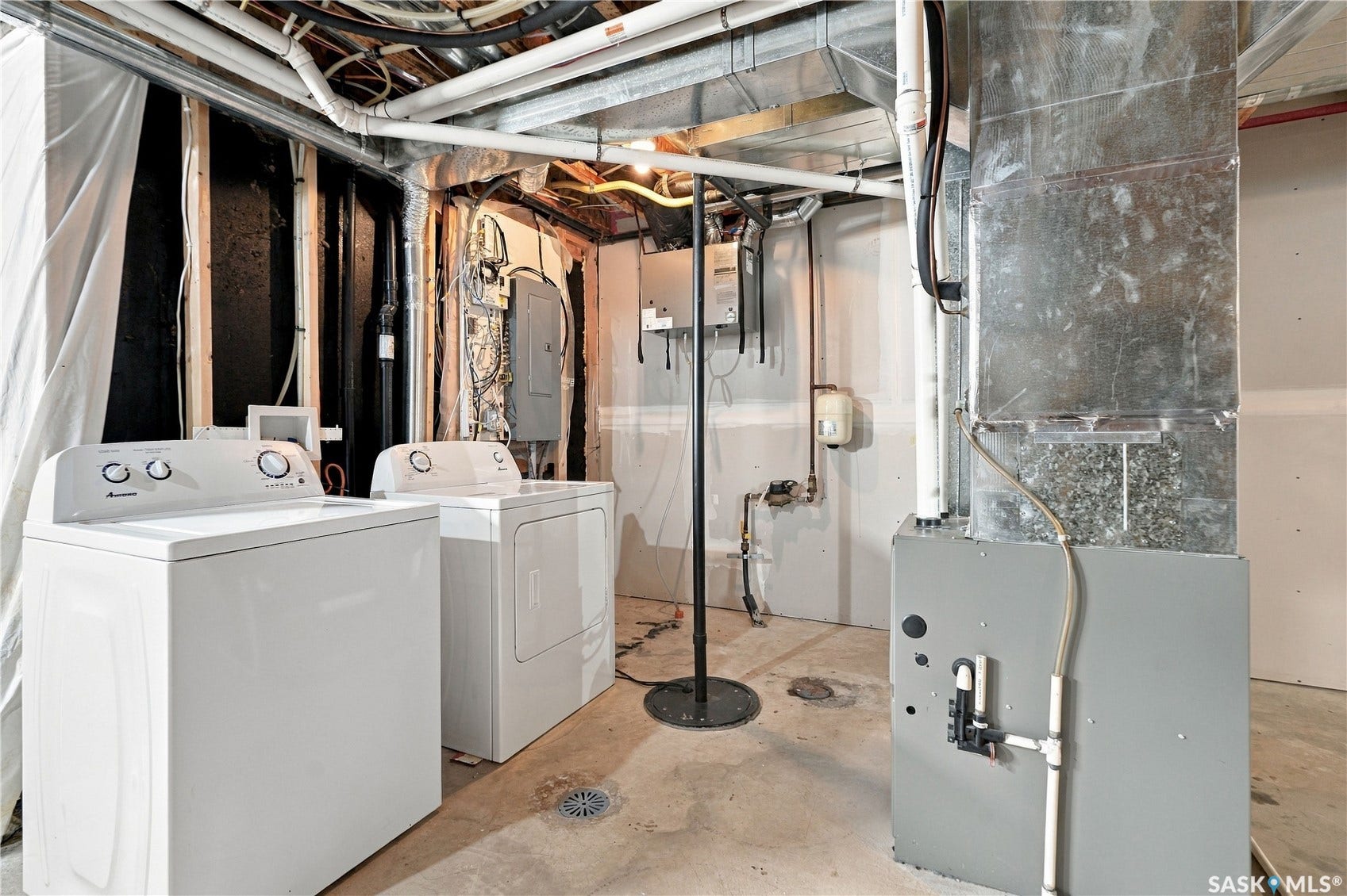 Finished concrete flooring, exposed ceiling utilities, drywall sections, and a floor drain