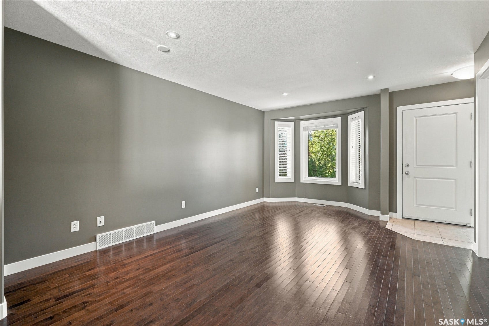 Hardwood flooring, recessed lighting, and a bay window with natural light