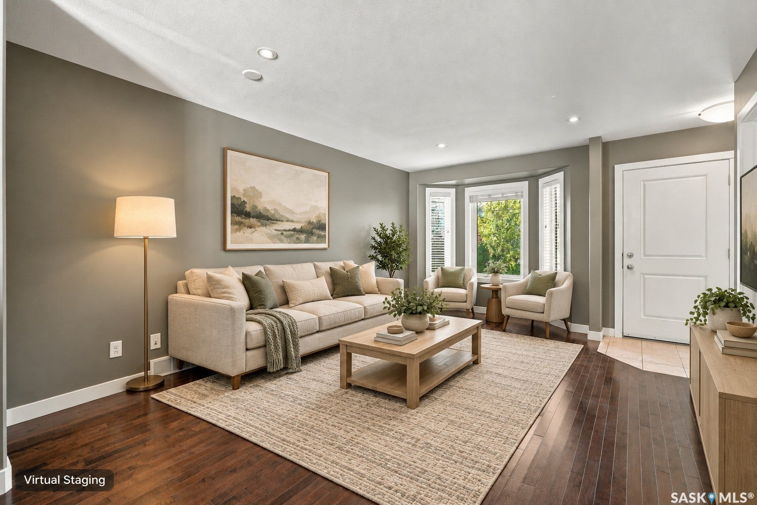 Rich wood-finish flooring, recessed ceiling lighting, a prominent bay window, and a white two-panel door