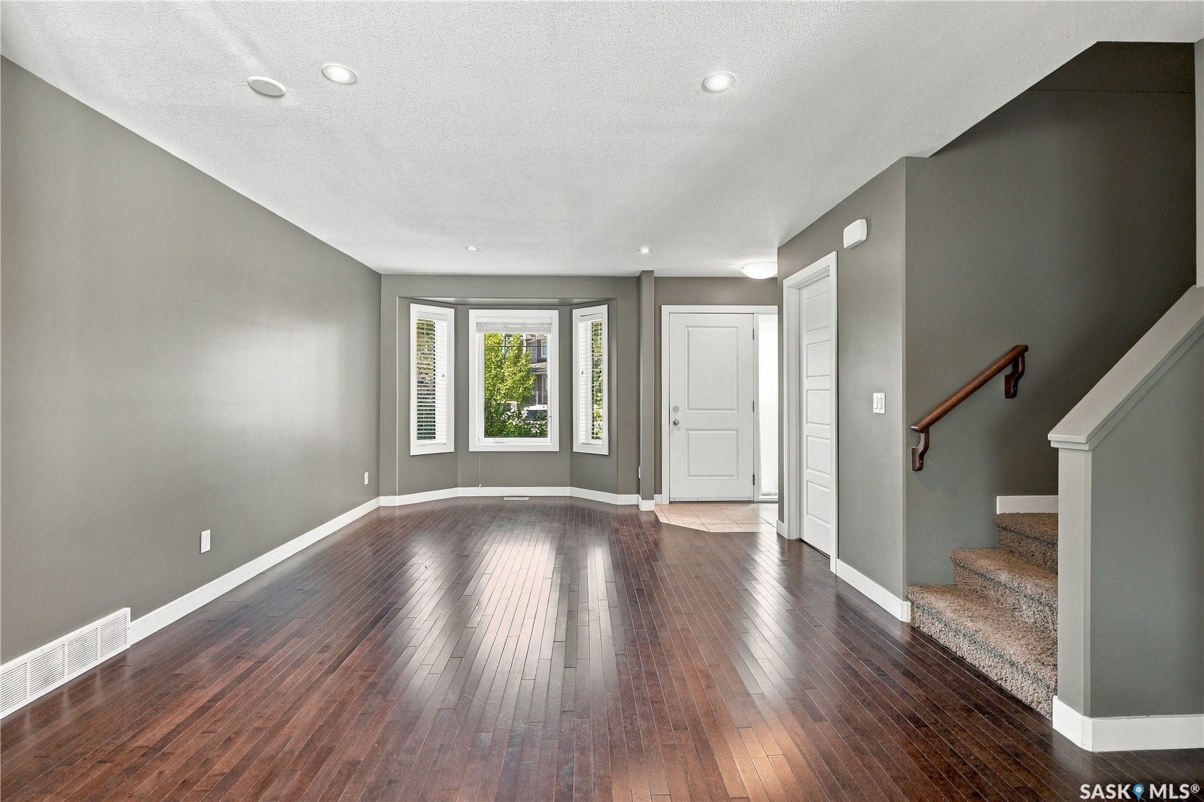 Wood-finish flooring, recessed lighting, bay window, and a carpeted staircase with a wood handrail