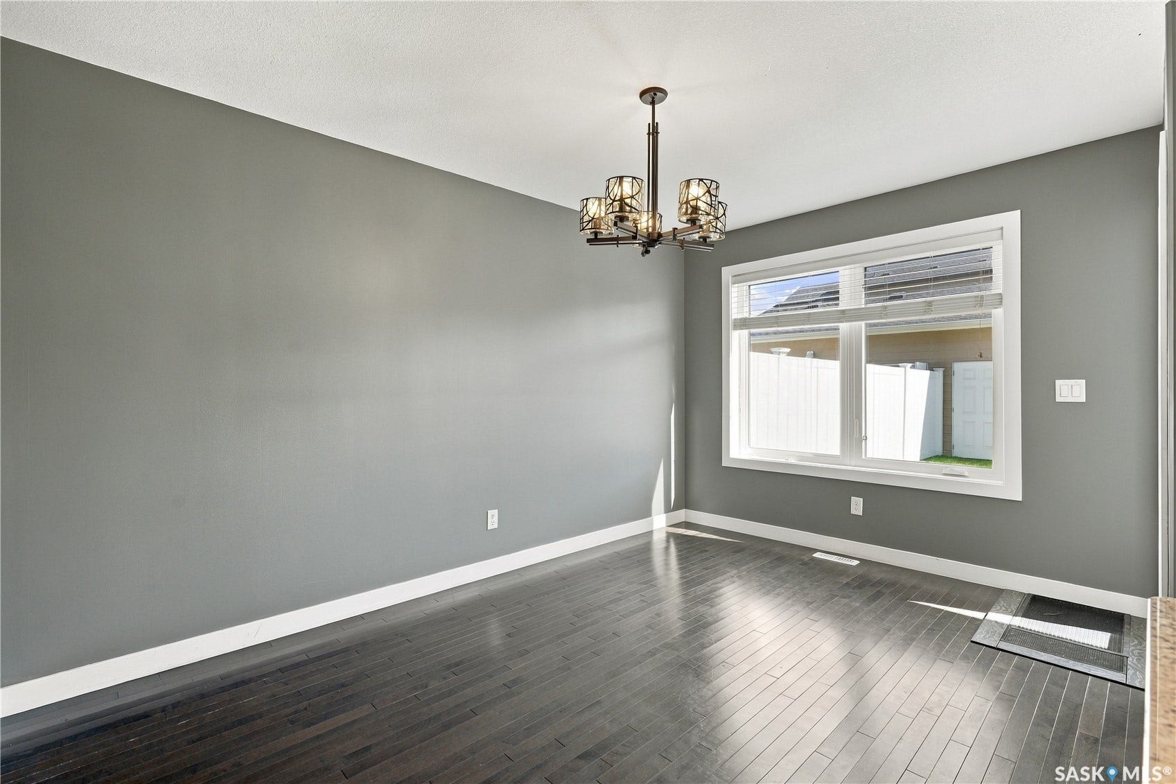 Hardwood-finish flooring, a contemporary chandelier, a large picture window, and neutral wall tones