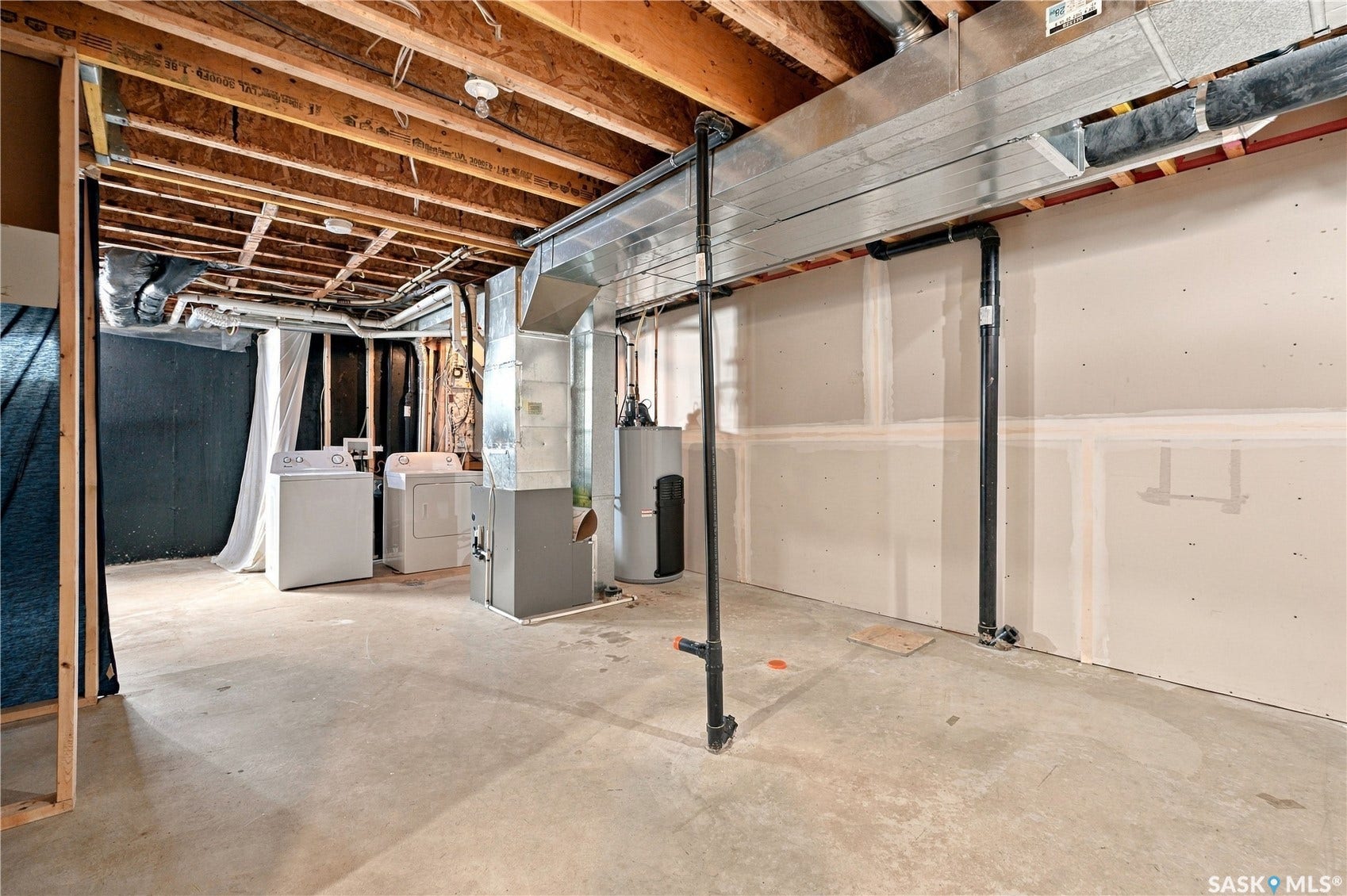 Unfinished lower level with exposed joists, concrete flooring, and partial drywall installation