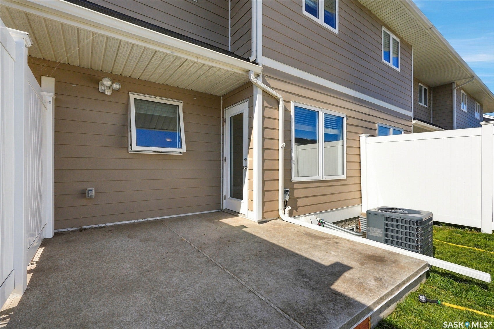 Concrete patio area featuring a privacy fence, exterior siding, and a rear entry door