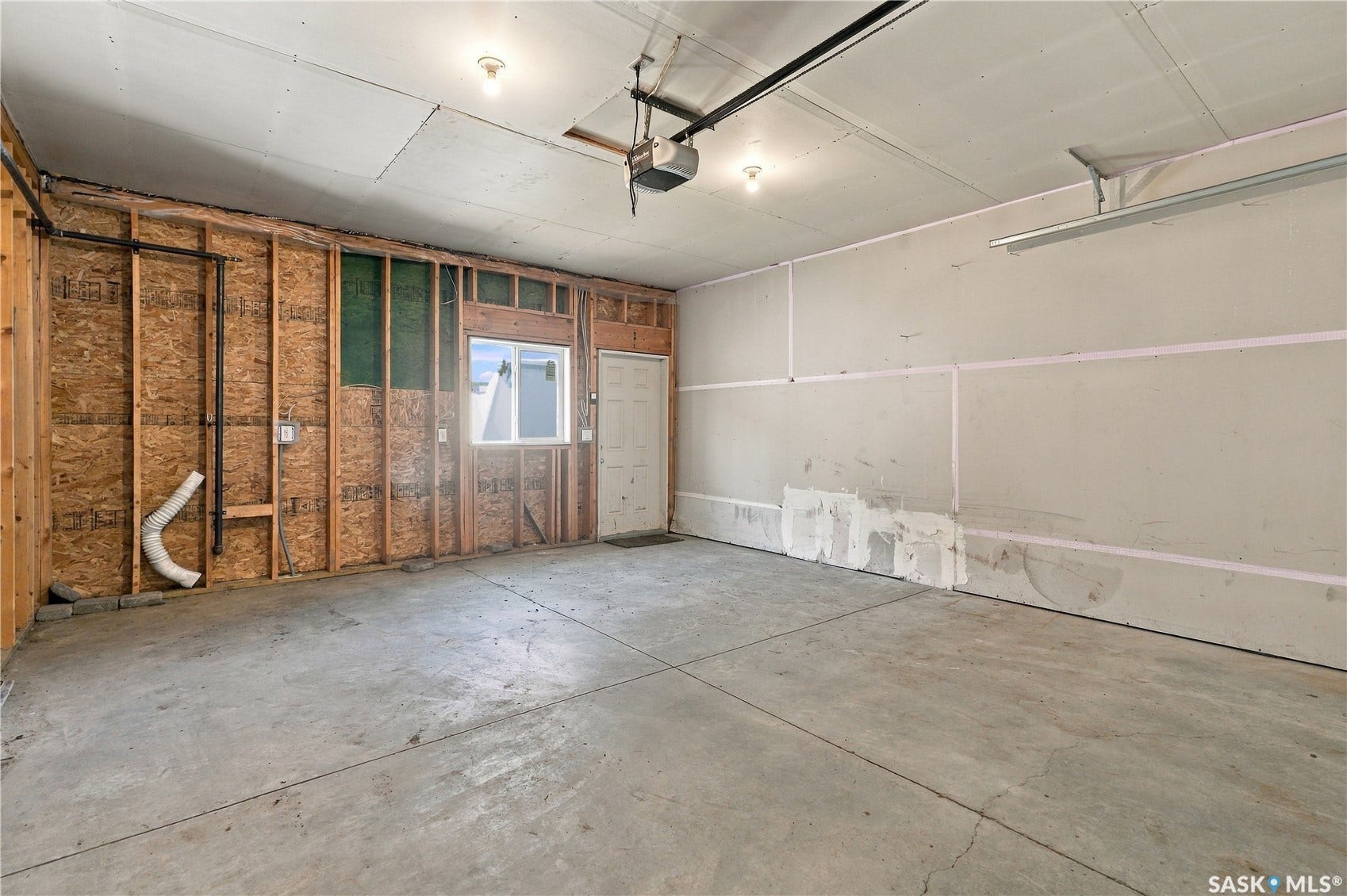 Garage space with concrete flooring, exposed studs, and a white framed window