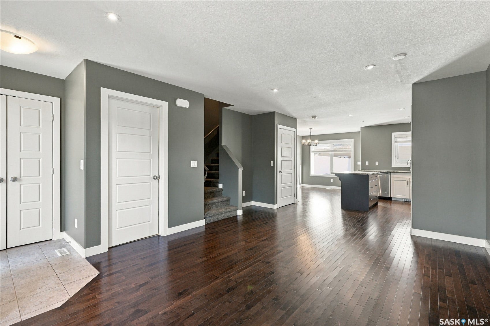 Hardwood flooring throughout, modern kitchen island, recessed lighting, white trim, and a contemporary chandelier