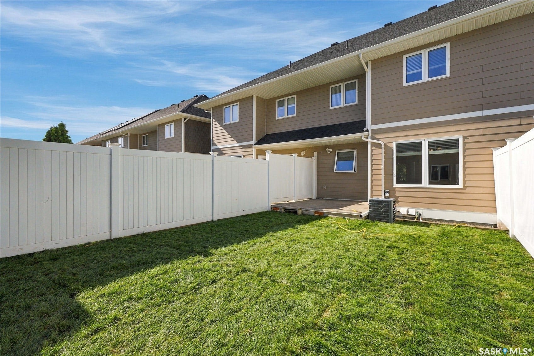Private fenced yard, ground-level patio, contemporary siding, multiple windows, and a dark shingled roof