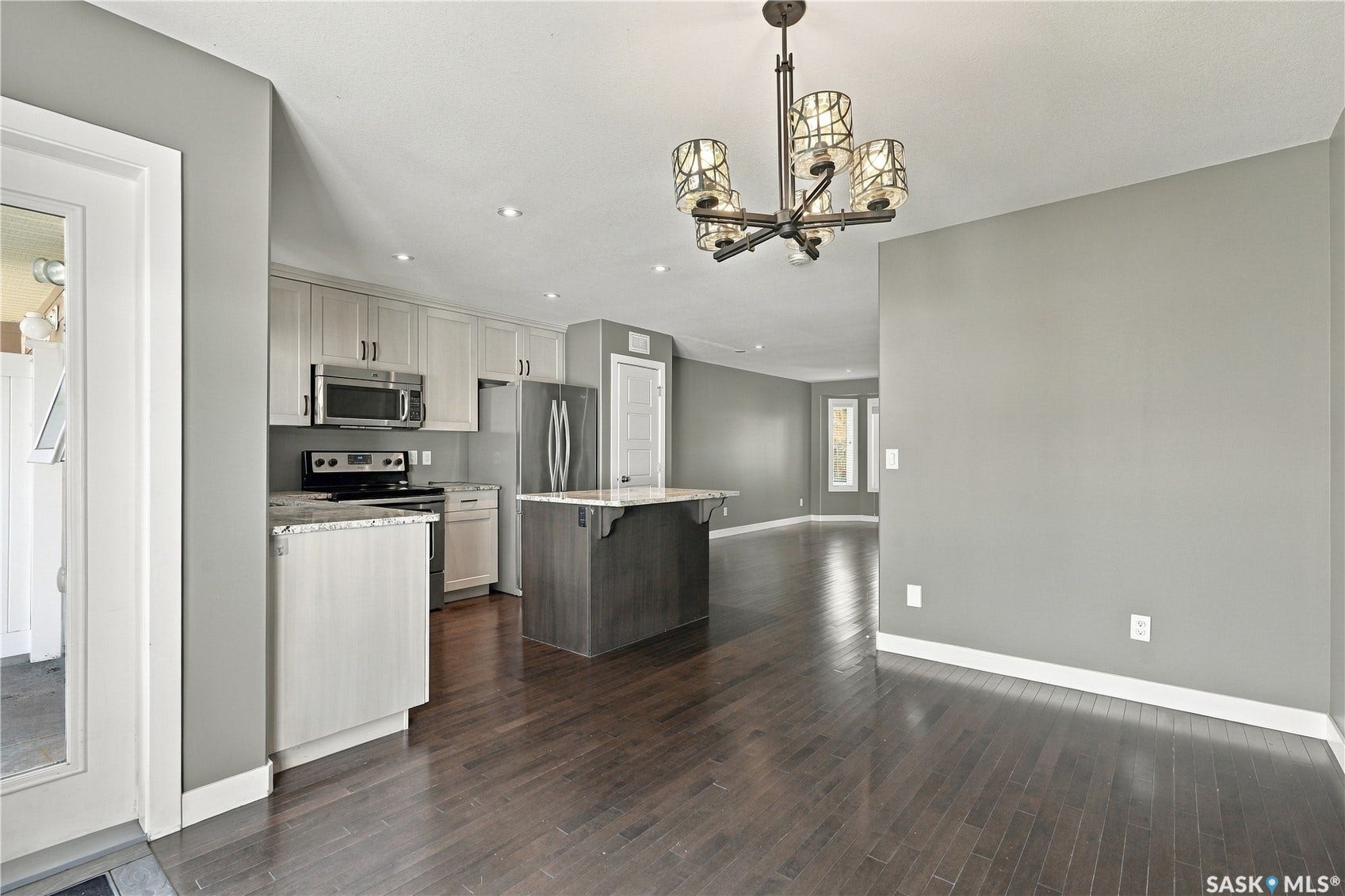 Open-concept living area featuring wood-finish flooring, recessed lighting, and a contemporary chandelier