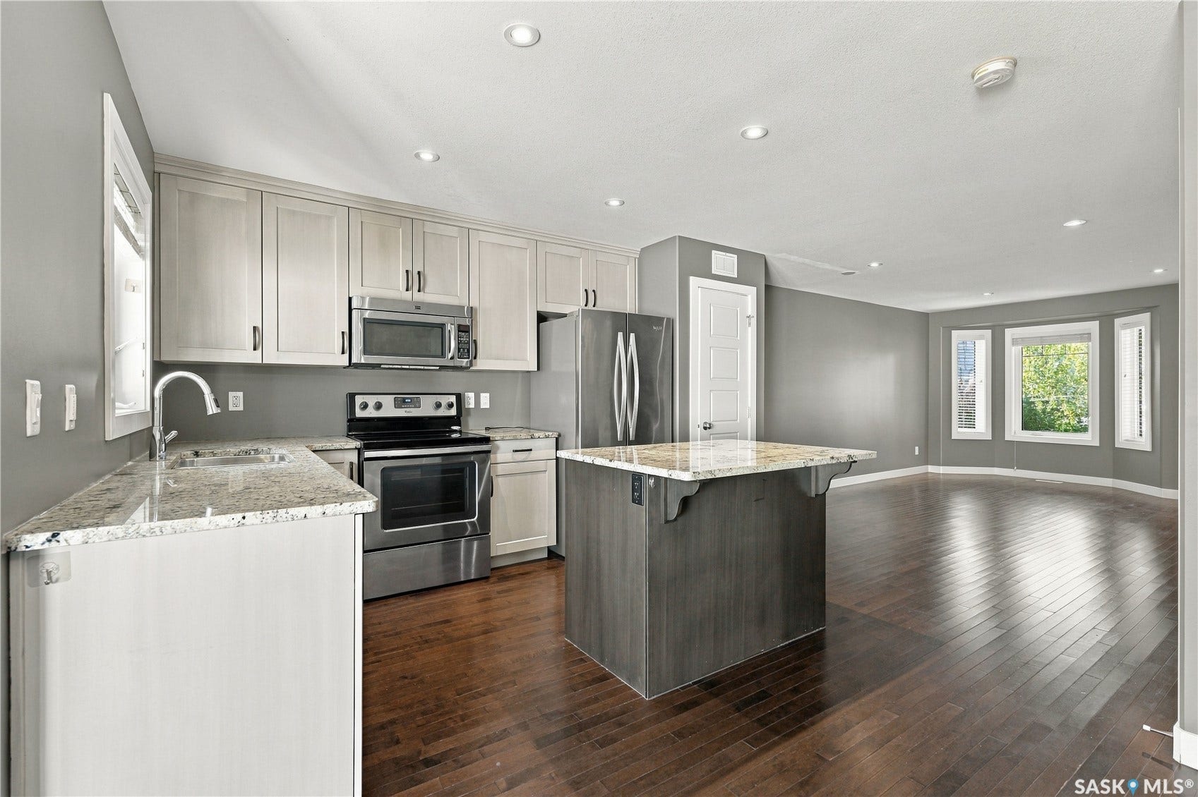 Kitchen featuring light-toned cabinetry, stainless steel appliances, and granite countertops, with a central island
