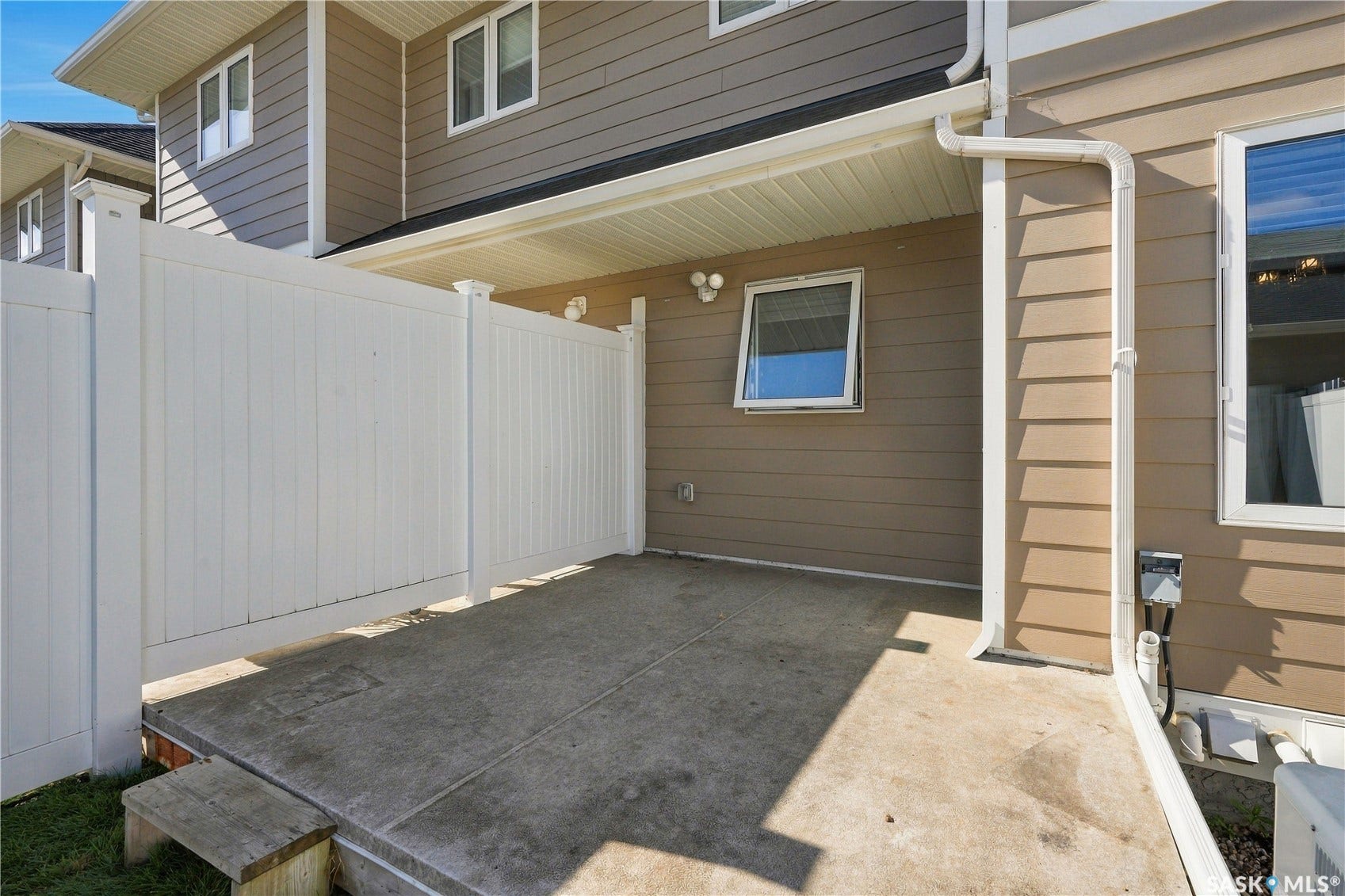 Concrete patio with white privacy fencing and beige siding