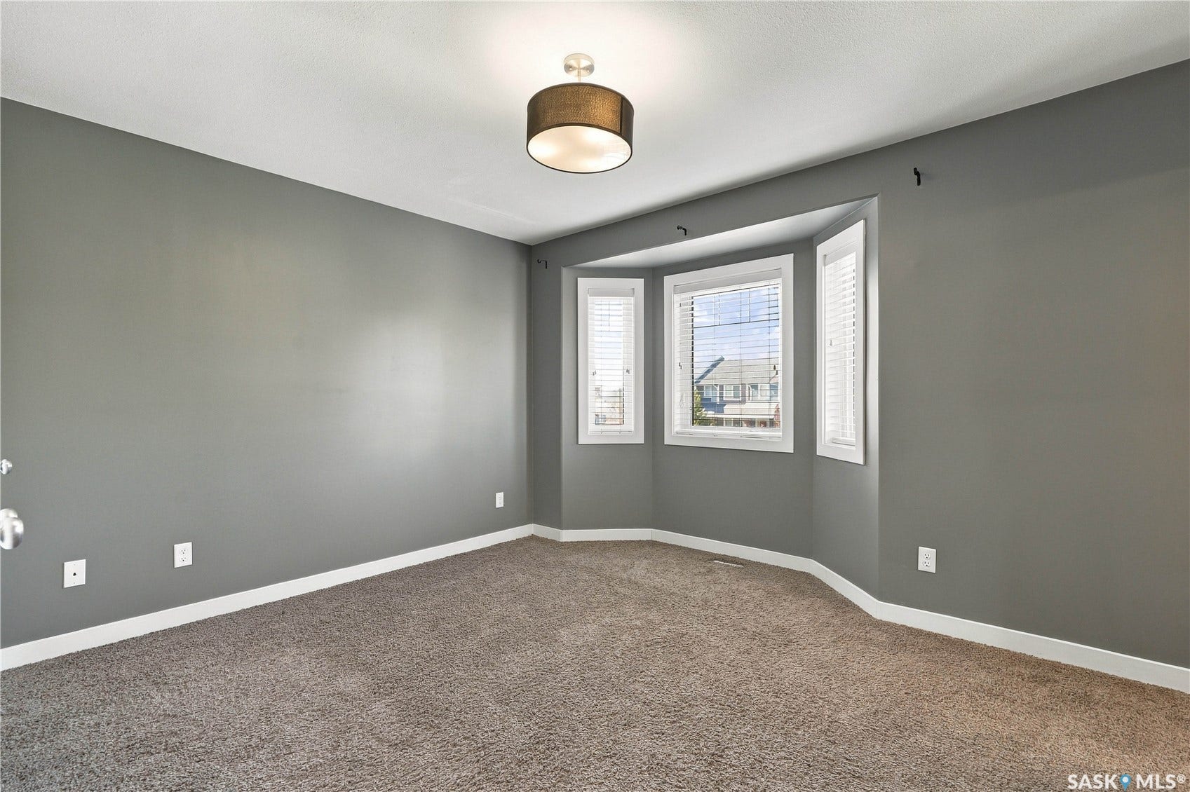 Bay window with white blinds, neutral carpeting, gray painted walls, white trim, and a contemporary ceiling fixture