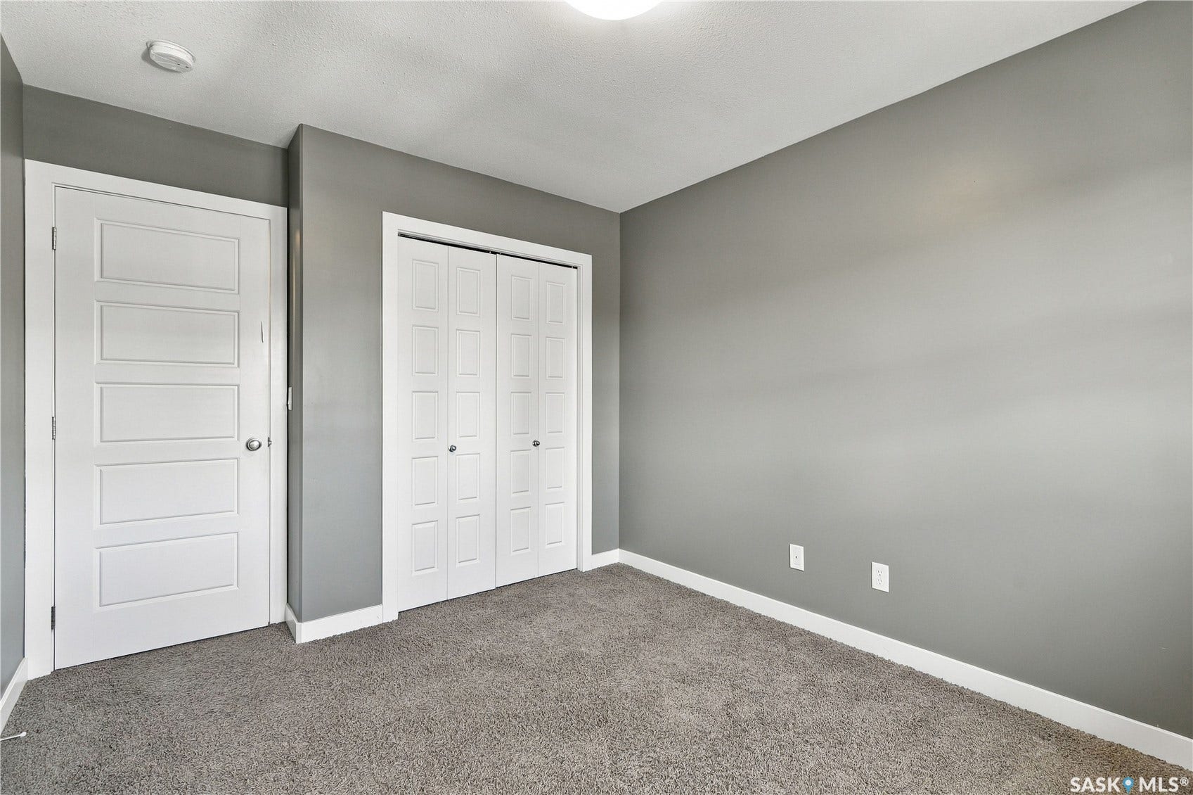 Wall-to-wall carpeting, modern flat panel interior door, contemporary gray wall finish, and bi-fold closet doors