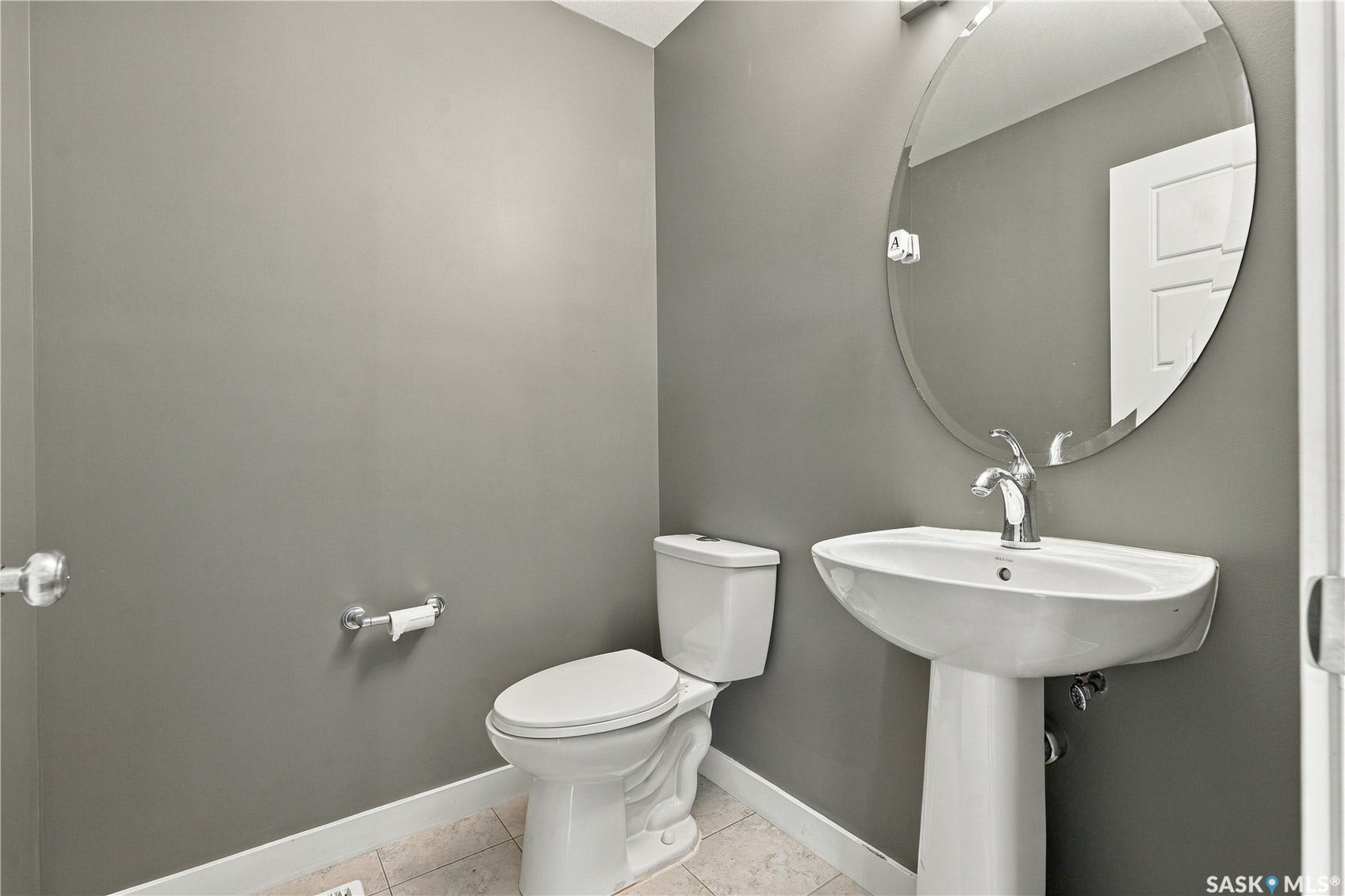 Pedestal sink with chrome faucet, oval mirror, and neutral wall color