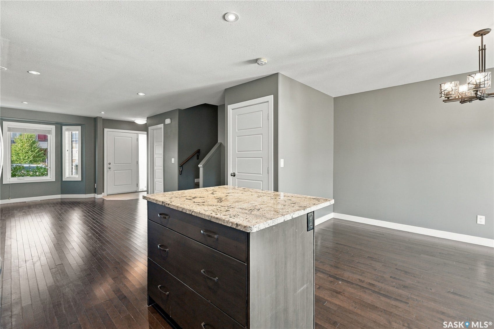 Hardwood-finish flooring throughout, featuring a kitchen island with stone countertop, recessed lighting, a decorative chandelier, and white paneled doors