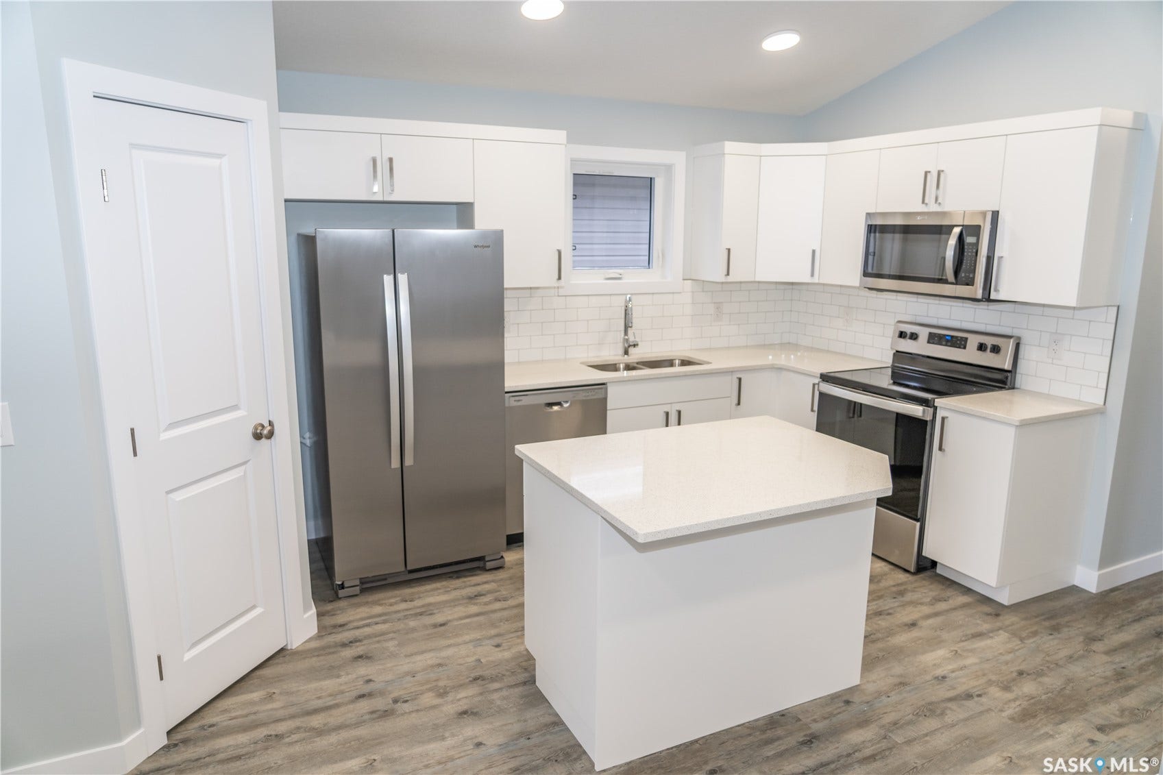 306 Stehwien Street, Saskatoon SK S7W 1P3 Kitchen with sink, stainless steel appliances, white cabinets, and light hardwood / wood-style flooring
