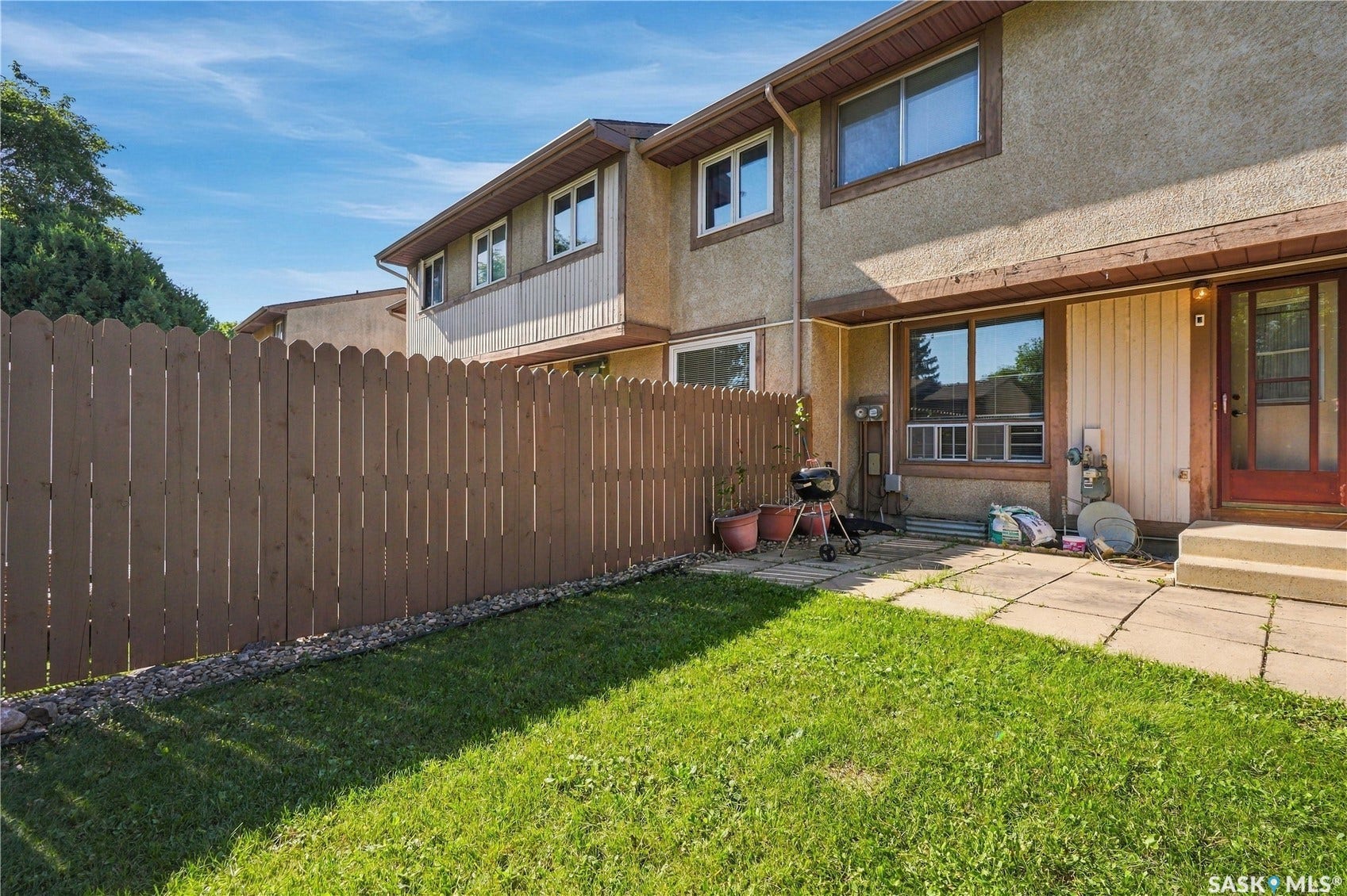 Private backyard featuring a wood fence, a grass lawn, and a stone patio