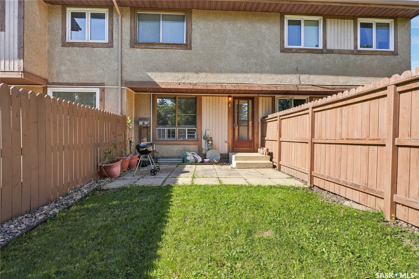 Fenced backyard featuring a lawn and a paved patio area