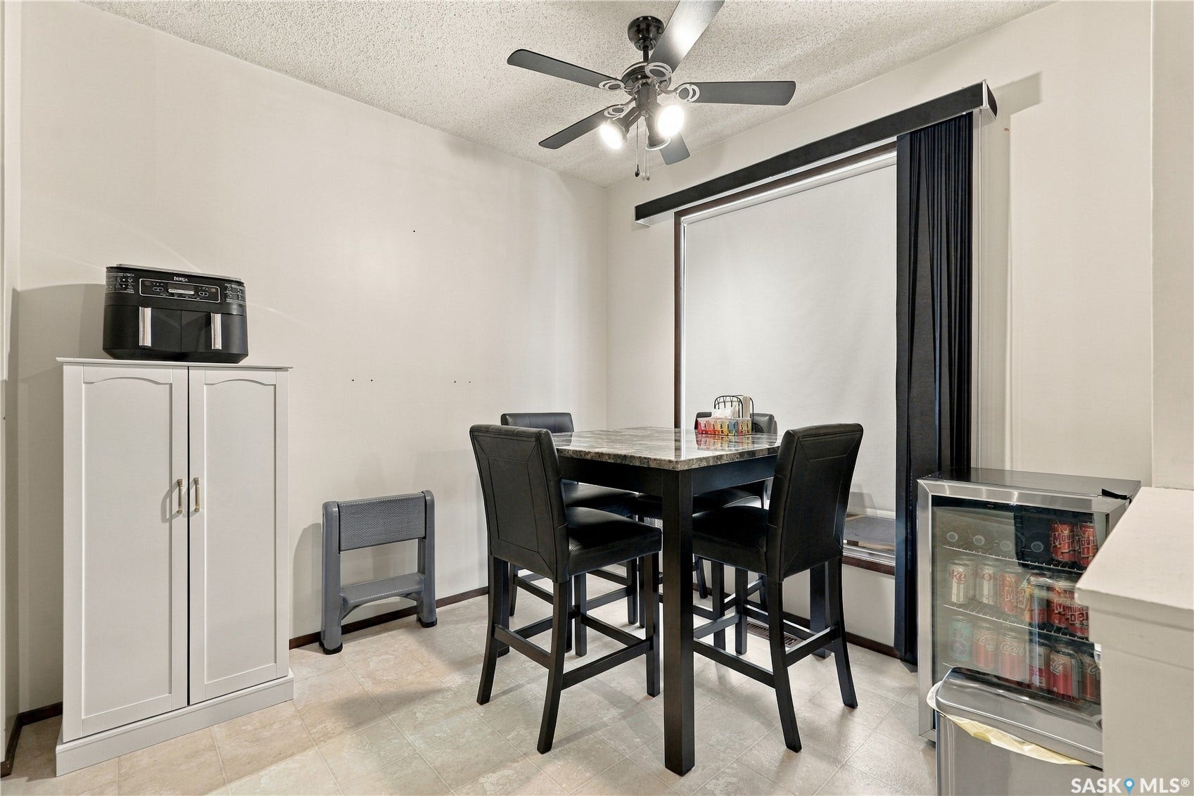 Ceiling fan with integrated lighting, window with dark blackout curtain, built-in storage cabinet with double doors, and light-toned flooring