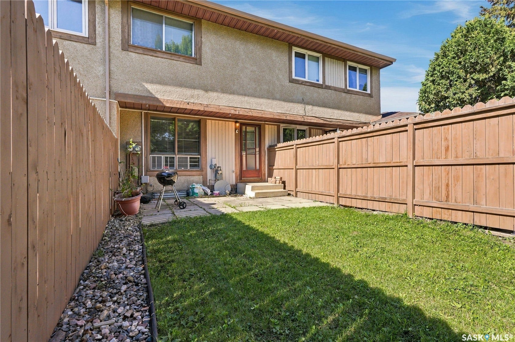 Private fenced yard featuring a grass lawn and stone-paved patio