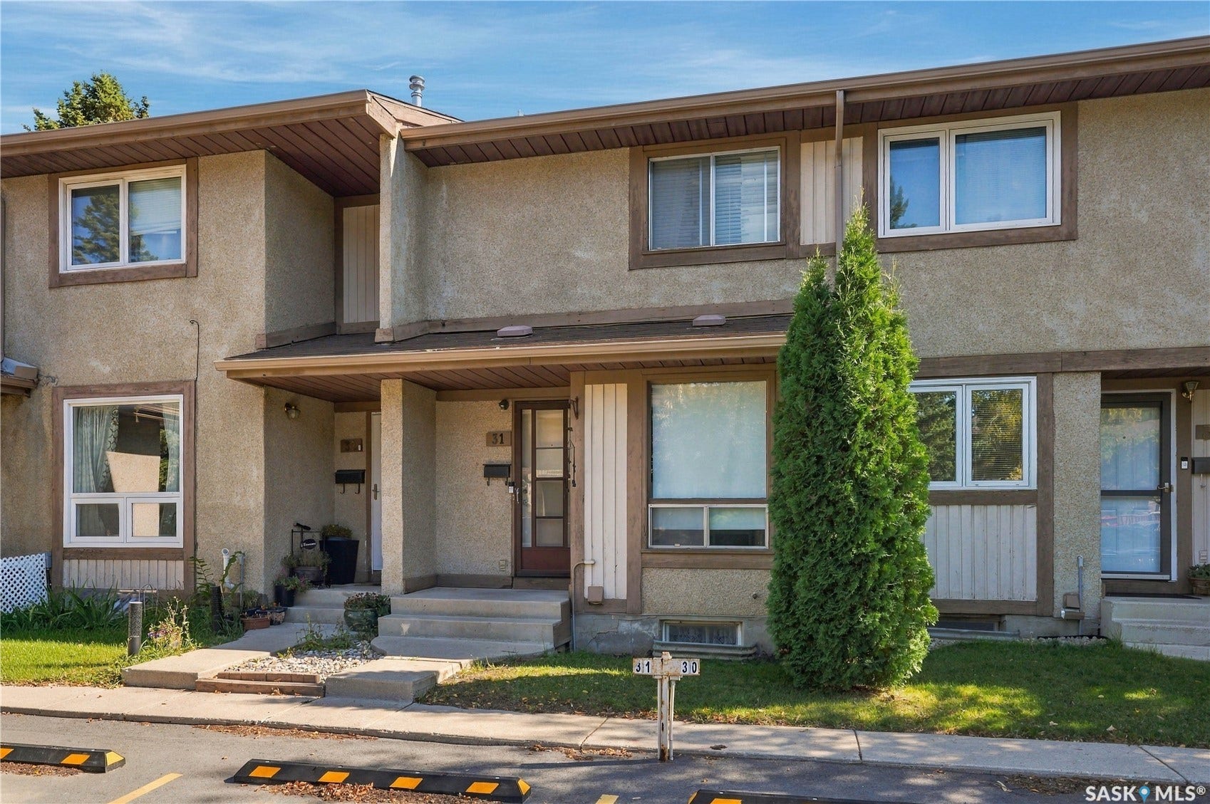 Stucco exterior with brown trim accents, multiple windows, and a covered entryway