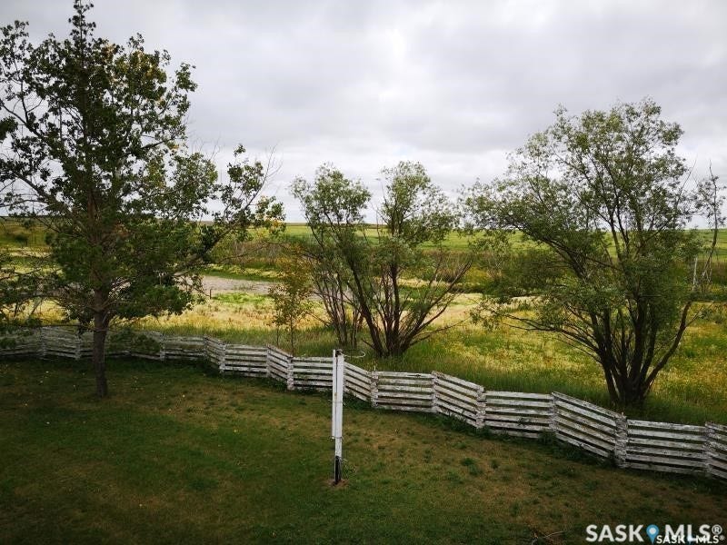 Expansive green lawn with mature trees and a rustic wood fence