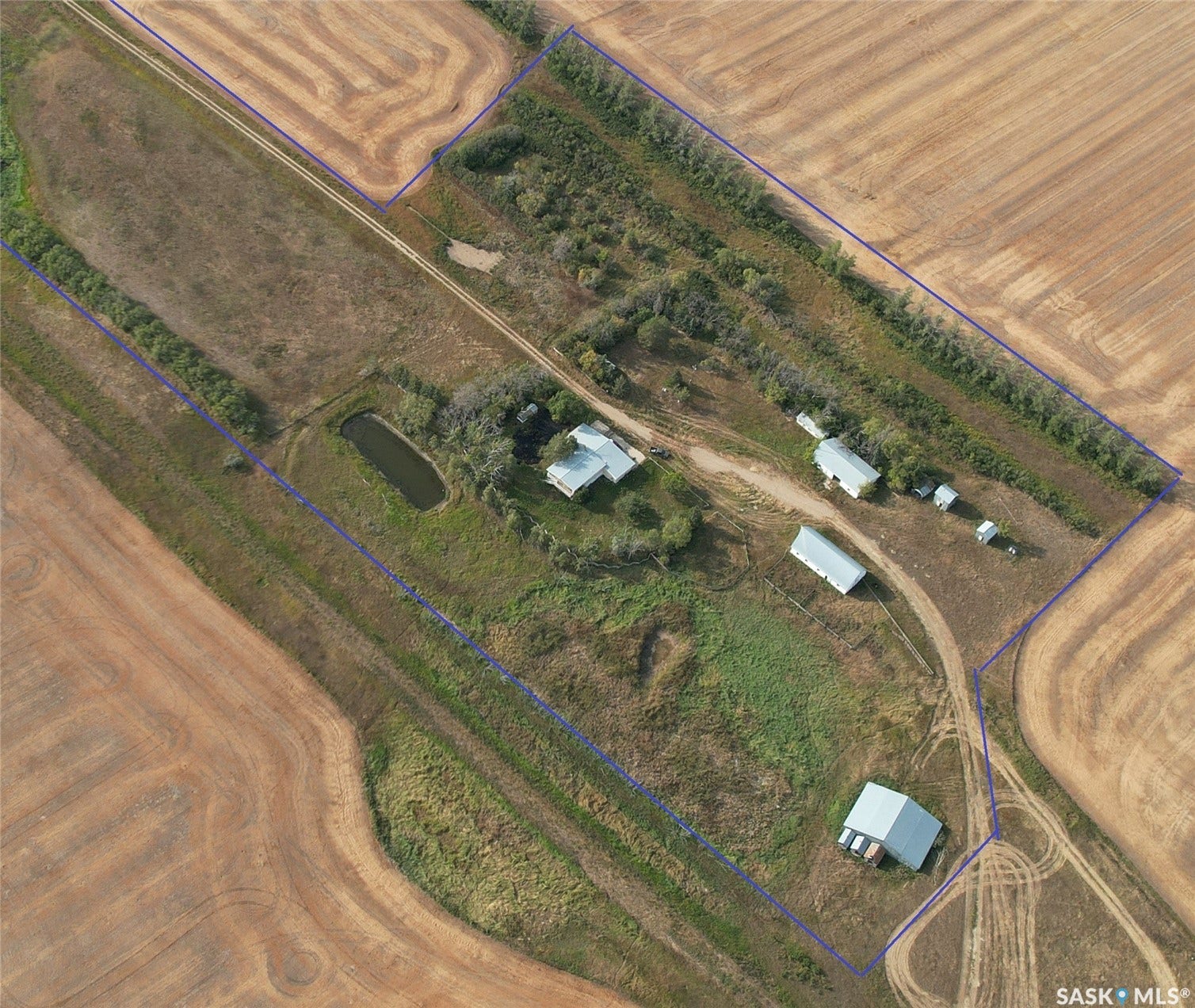 Expansive rural property featuring multiple structures, a visible pond, and agricultural land