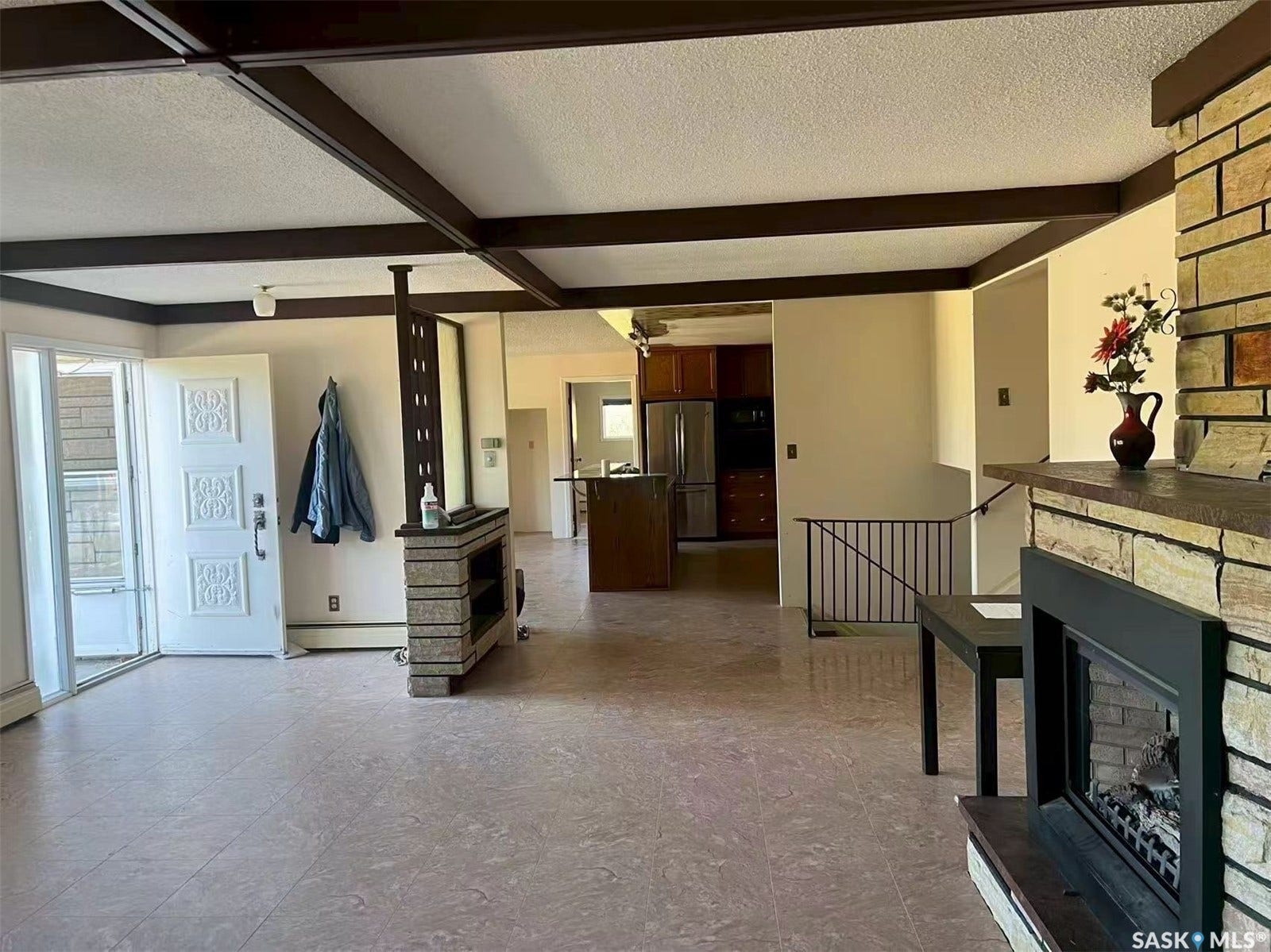 Exposed ceiling beams, stone-clad fireplace with hearth, and tiled flooring